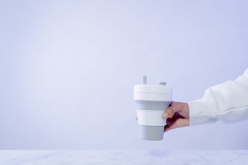 Close-up of a hand holding a collapsible cup against empty background.